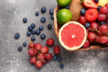 Wicker basket with different fresh fruits on grey table