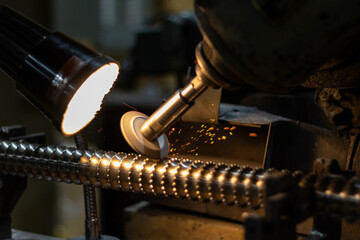 A spinning grinder machine  is sharpening the ridged edges on a broach tool inside of a manufacturing company.