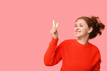 Beautiful young woman with tampons on pink background