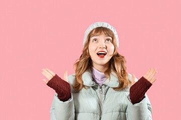 Smiling young woman in winter clothes on pink background