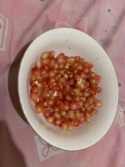 Delicious Red juicy Pomegranate grains seeds on a white plate 
