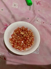 Delicious Red juicy Pomegranate grains seeds on a white plate 