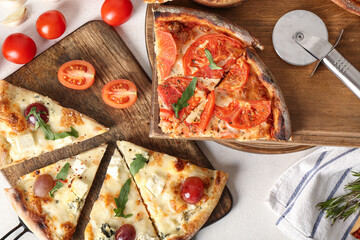 Wooden boards with delicious pizza slices, tomatoes and cutter on white background