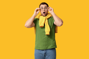Fototapeta premium Shocked young man in eyeglasses on yellow background