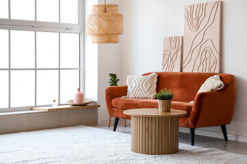 Light interior of stylish living room with cozy couch, coffee table and pictures