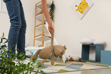 Woman taking toy bear from floor after earthquake in children's room