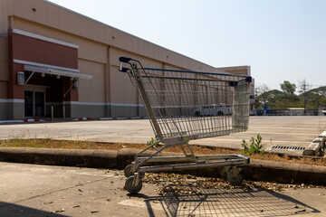 A lone shopping cart sits abandoned on the side of the road, symbolizing urban neglect and forgotten convenience. 