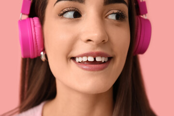 Fototapeta premium Young woman in headphones with diastema on pink background, closeup