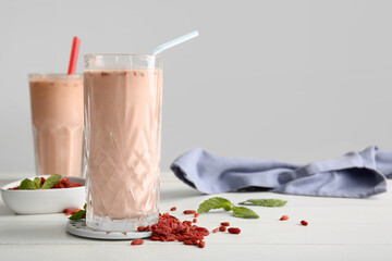Glasses of fresh goji berry smoothie with mint on white wooden table