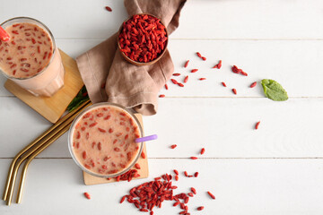 Glasses of fresh goji berry smoothie with mint on white wooden background