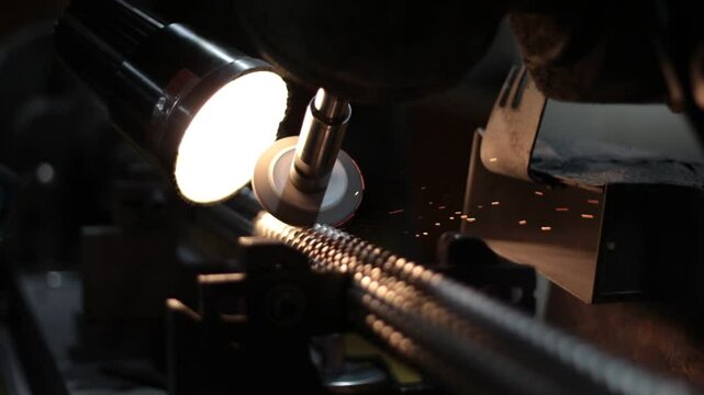 A spinning grinder machine is sharpening the ridged edges on a broach tool inside of a manufacturing company.
