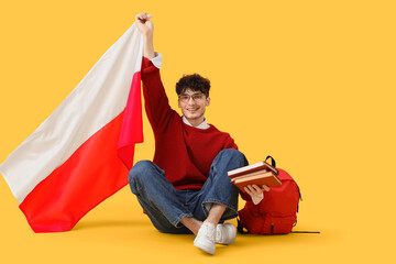 Male student with flag of Poland sitting on yellow background