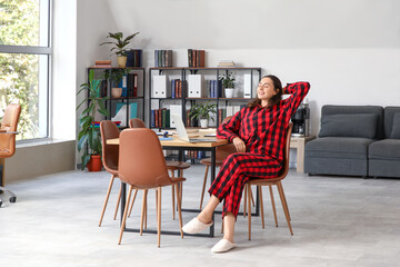 Young businesswoman relaxing in office. National Wear Your Pajamas to Work Day