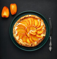 Persimmon orange pie, tart with ricotta on a black background. Top view. copy space