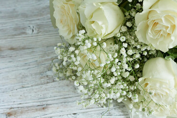 Bouquet of white roses and gypsophila on wooden background
