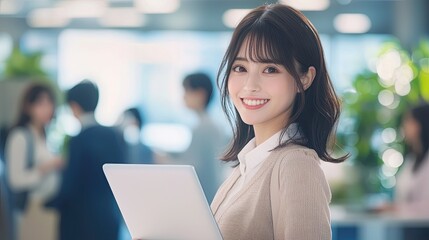 Smiling Japanese businesswoman standing in an office, holding her laptop. She is wearing casual clothes, and other people working behind her are blurred.,generated ai.  