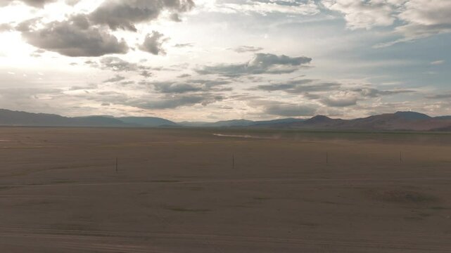 Aerial drone view of a traditional Mongolian eagle hunter on horseback, climbing a hill with the eagle in his arms, spectacular shot with the steppe in the background at sunset