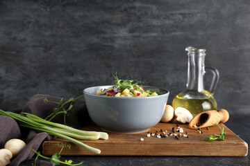 Bowl of tasty potato salad with onion and micro green on black background