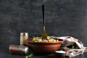 Bowl of tasty potato salad with onion and micro green on black background
