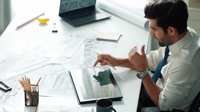 Architect engineer using laptop planning house design at office while sitting at meeting table with blueprint and equipment scatter around.Skilled civil engineer working at blueprint. Alimentation.