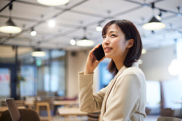 オフィス内でスマートフォンで電話をする日本人女性