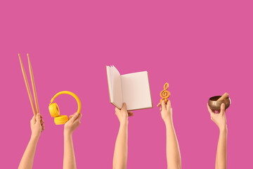 Female hands holding drumsticks with headphones, notebook and tibetan singing bowl on pink background