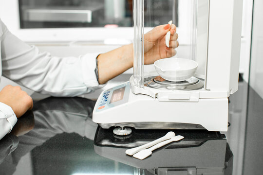 Precision weighing technique in a laboratory setting with a digital balance and measuring tools in use