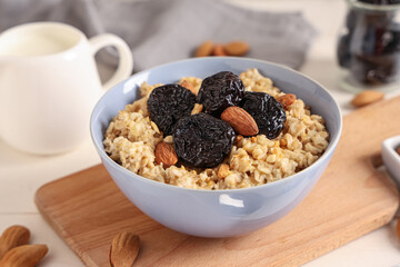 Bowl of tasty oatmeal with prunes and almonds, closeup