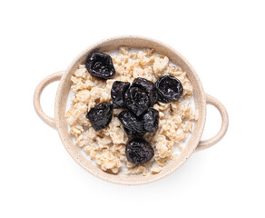 Pot of tasty oatmeal with prunes and milk on white background