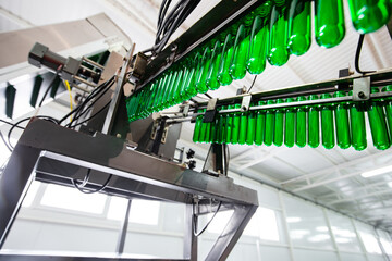 Production line in a factory showcases green glass bottles being filled with a liquid beverage