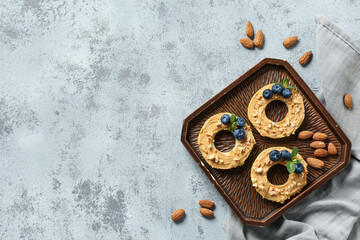 Wooden tray with tasty apple rounds, nut butter, blueberry, mint leaves and almonds on grey grunge background