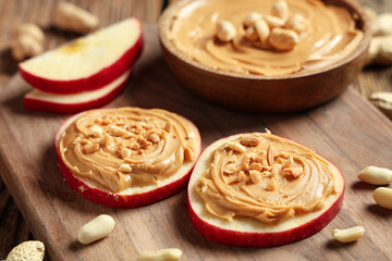 Wooden board with apple rounds, nut butter and peanuts, closeup