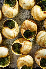 A dozen fresh snails cooked in a traditional French style, served in a small cast iron pan with garlic herb butter and parsley. The snails are plump and juicy, and the garlic herb butter