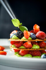A close-up of a dessert, showcasing the flaky layers of pastry, the juicy texture of the berries, and the creamy texture of the cream.