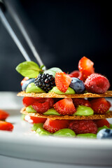 A close-up of a dessert, showcasing the flaky layers of pastry, the juicy texture of the berries, and the creamy texture of the cream.