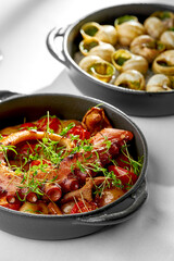 A close-up of a seafood dish, showcasing the tender texture of the octopus and the juicy texture of the snails.
