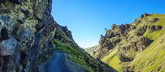 Winding road through a dramatic, rocky canyon under a clear blue sky.