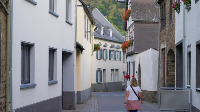 Rear view of a woman exploring narrow European streets in the old town village of Winningen, Mosel River Valley, Germany