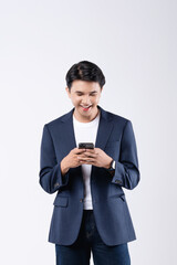 A man in a suit is smiling while looking at his cell phone