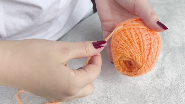 Women's hands unwind a ball of yarn for knitting. Yarn for crocheting and knitting. Handicraft lesson.