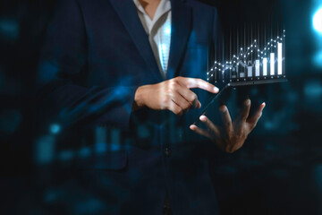 investment and finance concept, businessman holding virtual trading graph and blurred light on...