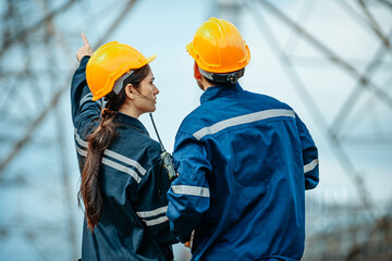 Engineers oversee power line construction at an electric facility during a clear day