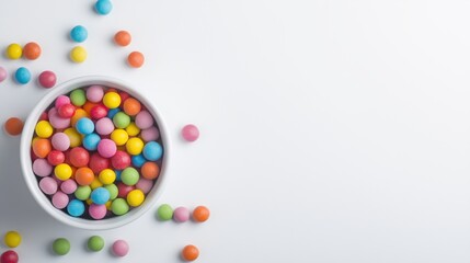 Obraz premium Bowl of colorful candies scattered on a white surface. Concept of fun, childhood, and sweet indulgence.
