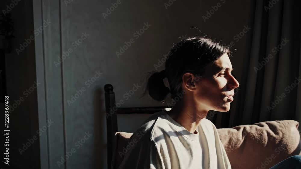 Aufkleber A serene moment of a person sitting by a window, gazing outside with sunlight streaming in, symbolizing deep thought and reflection.
