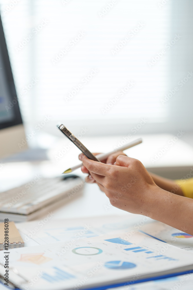 Poster professional setting with hands holding a smartphone, analyzing business charts and graphs on paper 