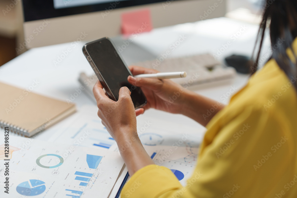 Poster business professional using a smartphone to analyze data, with charts and graphs on the desk. the se