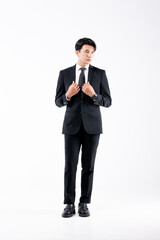 A man in a black suit and tie stands in front of a white background