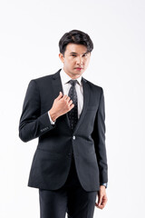 A man in a black suit and tie stands in front of a white background