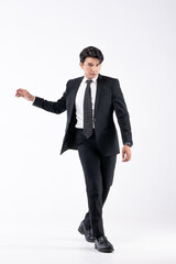 A man in a black suit and tie stands in front of a white background