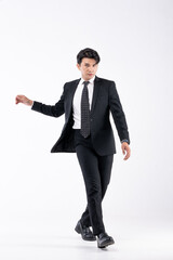 A man in a black suit and tie stands in front of a white background